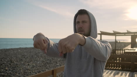 man doing boxing workout on the beach at sunrise