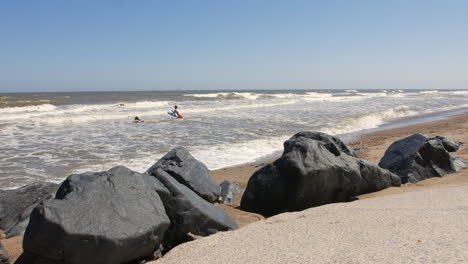 a view from the beach of two bodyboarding girls playing with bodyboards in the sea