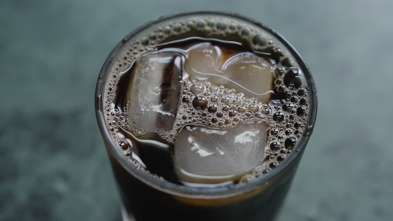 A close-up, top view of a glass of iced tea with ice cubes, with blurred background