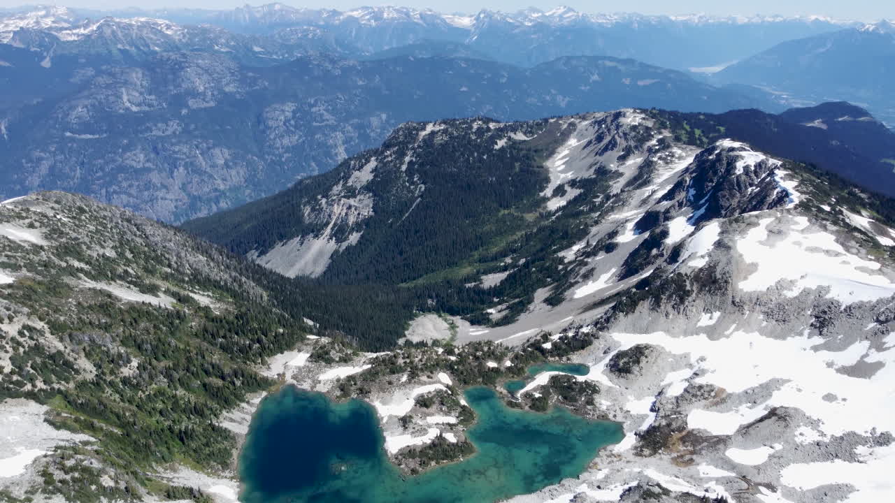 캐나다 슈거로프 피크에 있는 펨버튼 메도우 근처의 흐릿한 산 풍경을 드러내는 청록색 호수의 공중 전망 - 드론 영상 4k