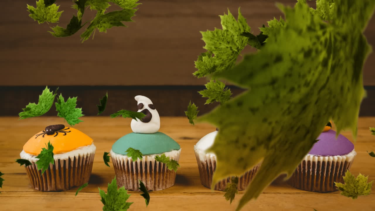 Digital Composite video of autumn leaves falling against Halloween cupcakes in background