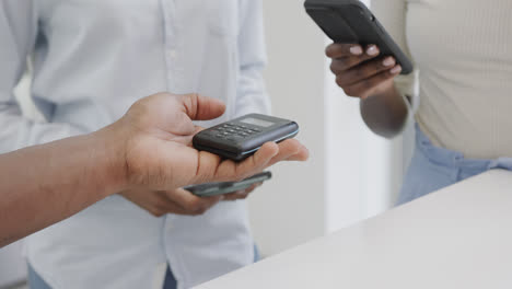 midsection of african american woman paying for takeaway coffee in cafe with smartphone, slow motion