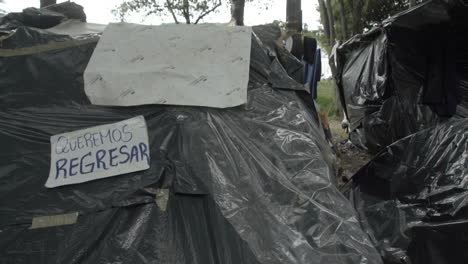 we want to go back! sign at venezuelan migrant camp. because of the covid-19 crisis many migrants in colombia try to return to their country. they lost their jobs and cant pay rent.