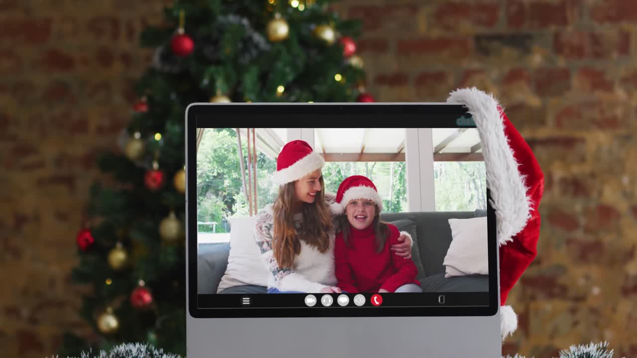 madre y hija felices con sombreros de santa en una videollamada en la computadora, con decoraciones de navidad