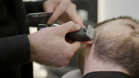 barbero recortando la barba de un hombre