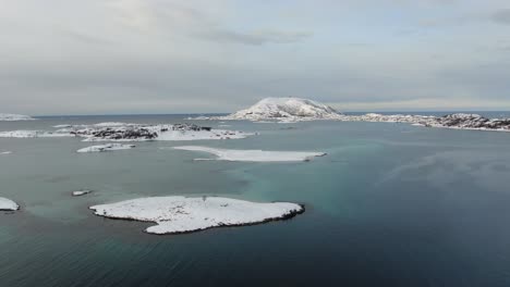 drone view in tromso area in winter flying over a snowy islands surrounded by the sea in norway