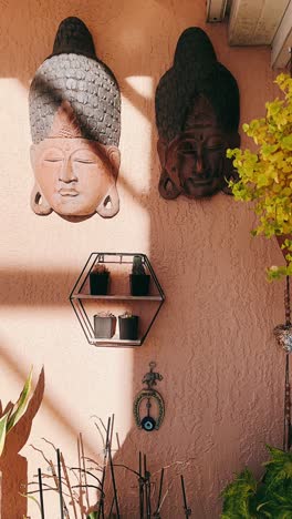 buddha heads and plants on a pink wall