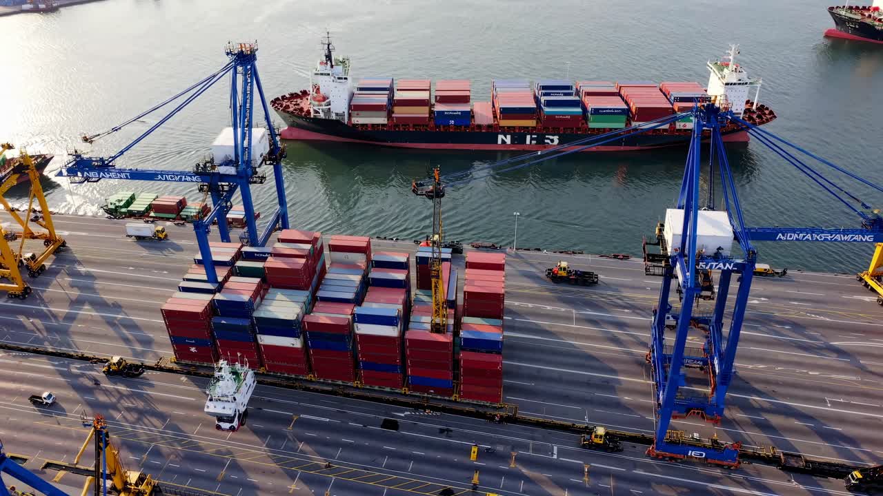 Aerial video of a bustling port with cranes and cargo ships
