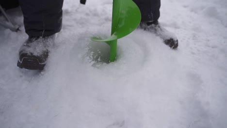 man drilling on ice using auger drill - ice fishing at sodus bay in winter