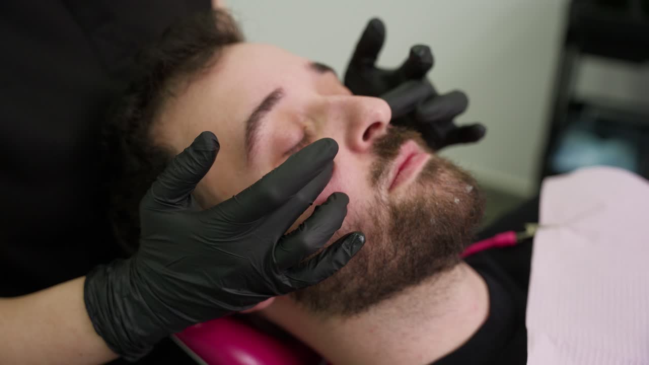 Man Receiving Facial Treatment with Gloved Hands