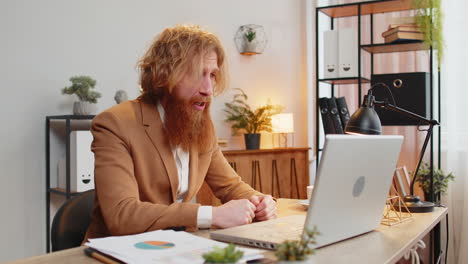upset business man arguing on laptop call online displaying report charts graphs home office table