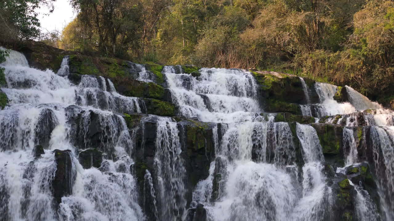 Majestic cascading waterfall, close-up view of rushing water over mossy rocks
