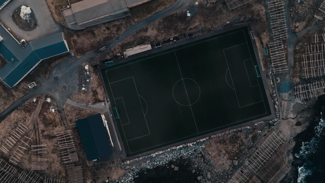 Reine, Lofoten Islands, Nordland, Norway - Stockfish Racks Cling to the Rocky Shore as Arctic Waves Crash Below - Aerial Topdown Shot
