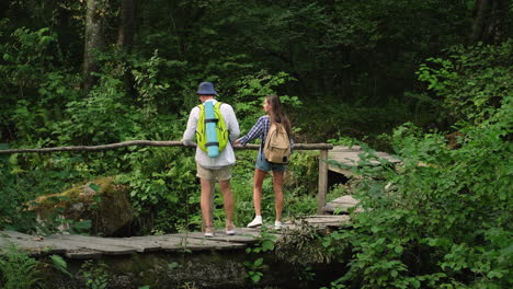 pareja de senderismo en un puente de madera en un bosque