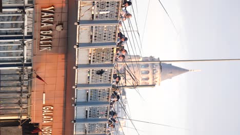people fishing from galata bridge with galata tower in the background, istanbul