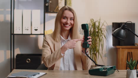 Young-smiling-businesswoman-talking-on-wired-vintage-telephone-of-80s,-says-hey-you-call-me-back