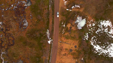 aerial birdseye view of a travel van on a dirt road with scattered snow coverage