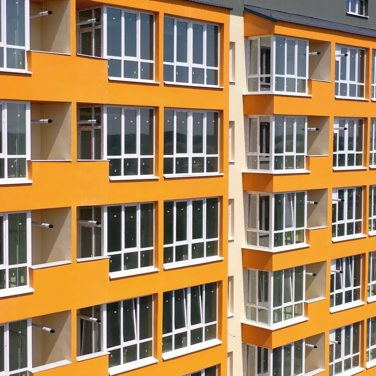 Novo edifício de vários andares na cidade. Design moderno de edifício de apartamentos com paredes laranja e grandes varandas. Fachada de casa de luxo para moradores da cidade.