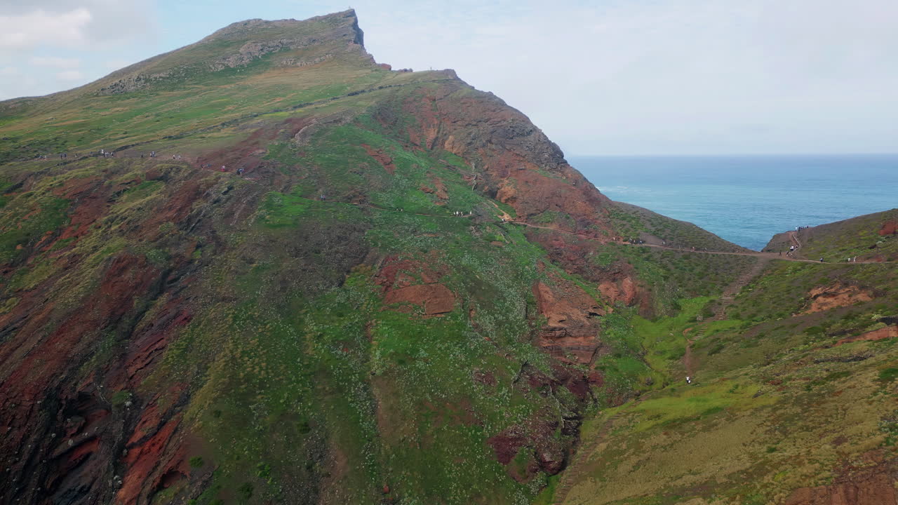 Drone rocky mountain cliff at calm ocean. Hikers exploring rugged hillside
