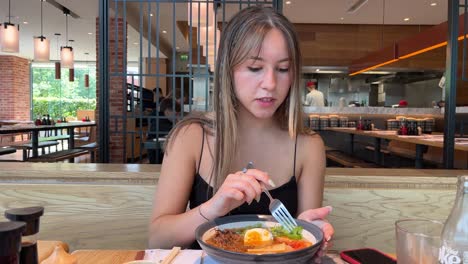 una joven feliz comiendo fideos ramen en un lujoso restaurante japonés en un caluroso día soleado en inglaterra