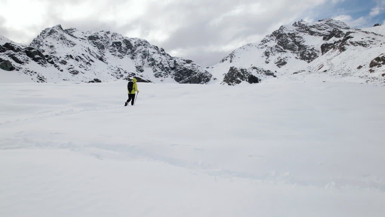 vista aérea de un alpinista que avanza en montañas nevadas en un día soleado en los alpes europeos