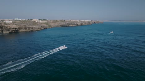 Toma-Aérea-De-Un-Barco-Moviéndose-Rápidamente-En-El-Mar-Con-Vistas-A-La-Costa-En-Peniche-Portugal