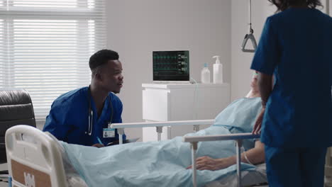 caring african ethnic medical team at the bedside of an elderly male patient. caring health care providers monitor vital signs of an elderly male hospital patient