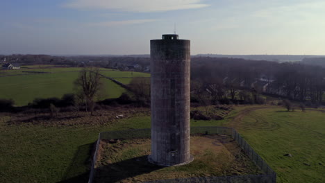 establishing aerial shot of a cylindrical water tower, well-framed and orbiting to reveal the surrounding irish landscape