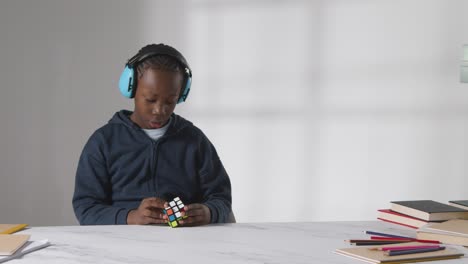 studio shot of boy on asd spectrum solving puzzle cube wearing ear defenders