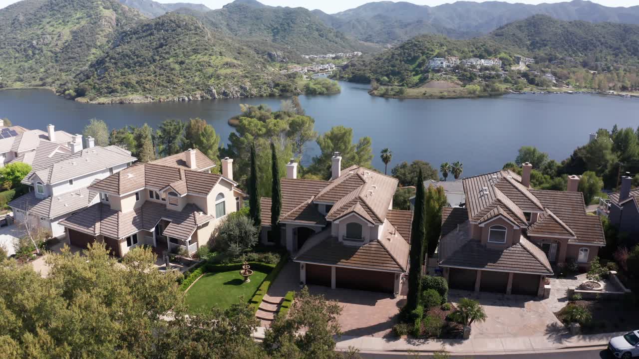 Aerial close-up panning shot of lakeside luxury homes in Lake Sherwood, California. 4K at 30 FPS