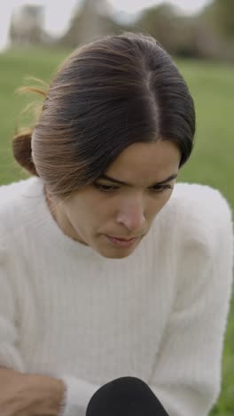 a woman looking down in a white sweater outdoors