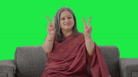 vieja india feliz mostrando el signo de la victoria pantalla verde