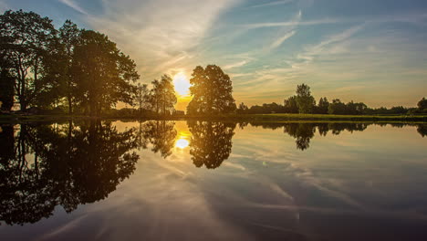 Ruhige-Sonnenaufgangslandschaft-Mit-Seewasser-Und-Silhouette-Von-Bäumen,-Zeitraffer