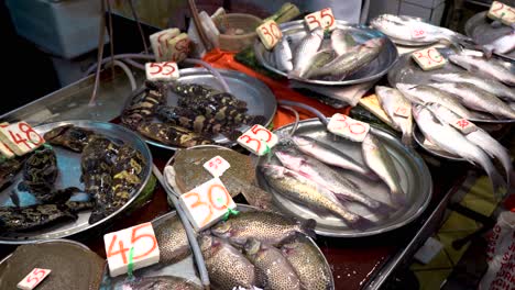 variety of live fishes with price tags selling in wet fish market, hong kong