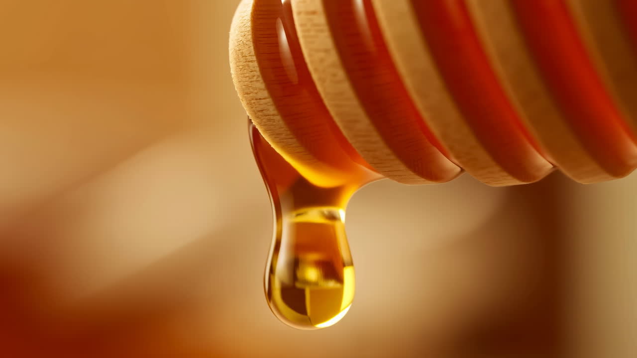 Miele dorato che cola lentamente da un mestolo di legno