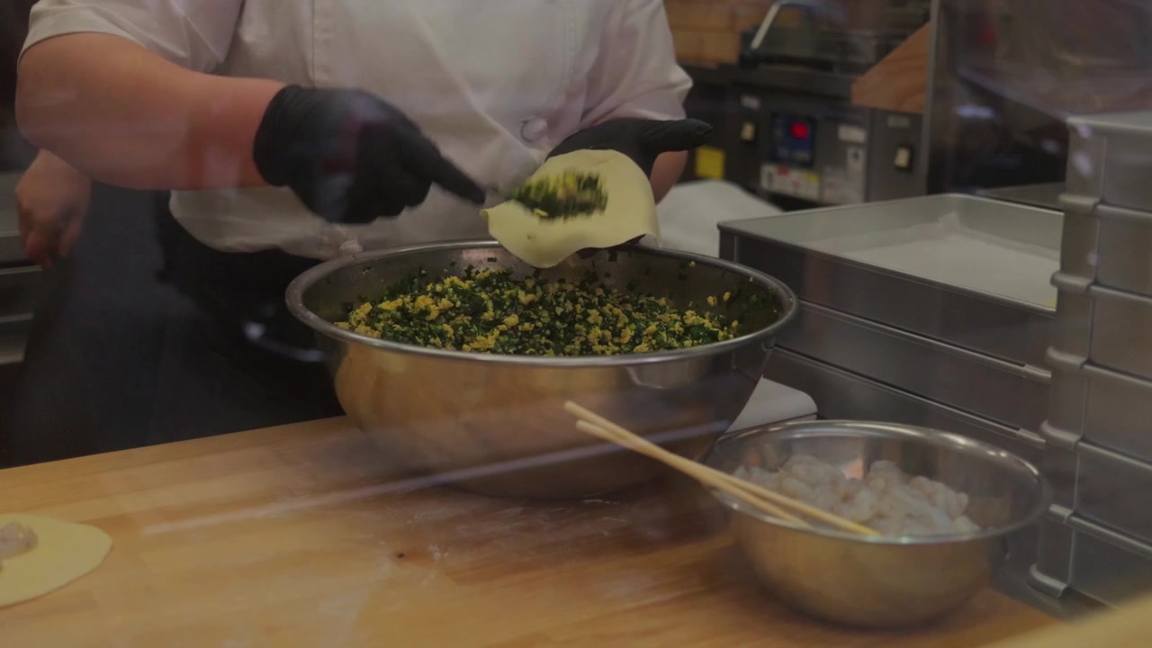 Vista ravvicinata di uno chef che prepara cibo fresco all'interno di una cucina di ristorante in Giappone. Autentico filmato culinario che mostra mani, ingredienti e processo di preparazione del cibo