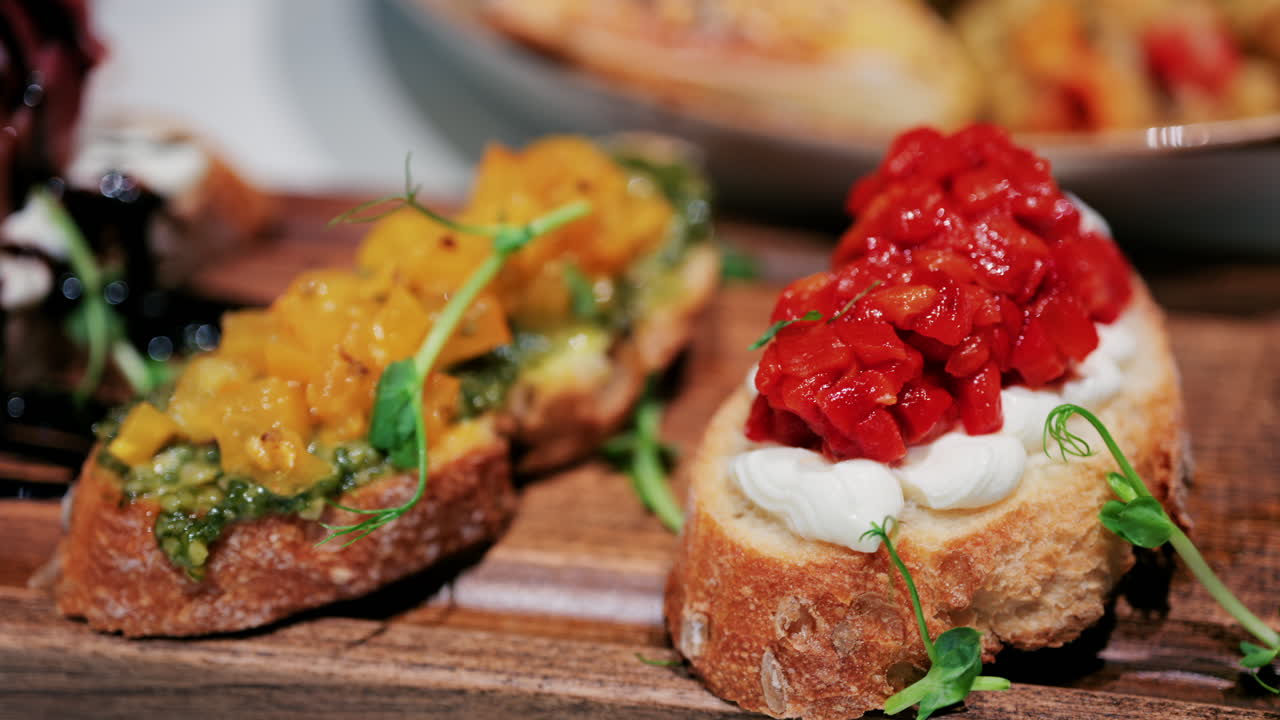 Close up of rustic bruschetta topped with cream cheese and roasted red peppers, garnished with fresh greens