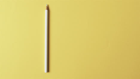 Overhead-view-of-white-crayon-with-copy-space-on-yellow-background,-in-slow-motion