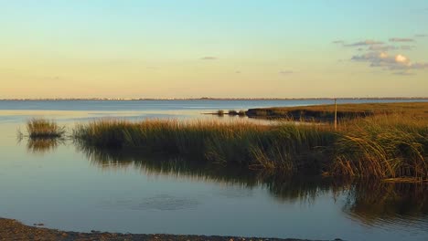 hd 120 fps pan left to right from waterway view with tall grass to reveal atlantic city skyline in distance with mostly clear sky near golden hour