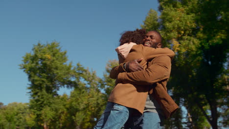 Loving-dad-spinning-kid-embracing-joyful-cute-daughter-in-spring-sunny-park.