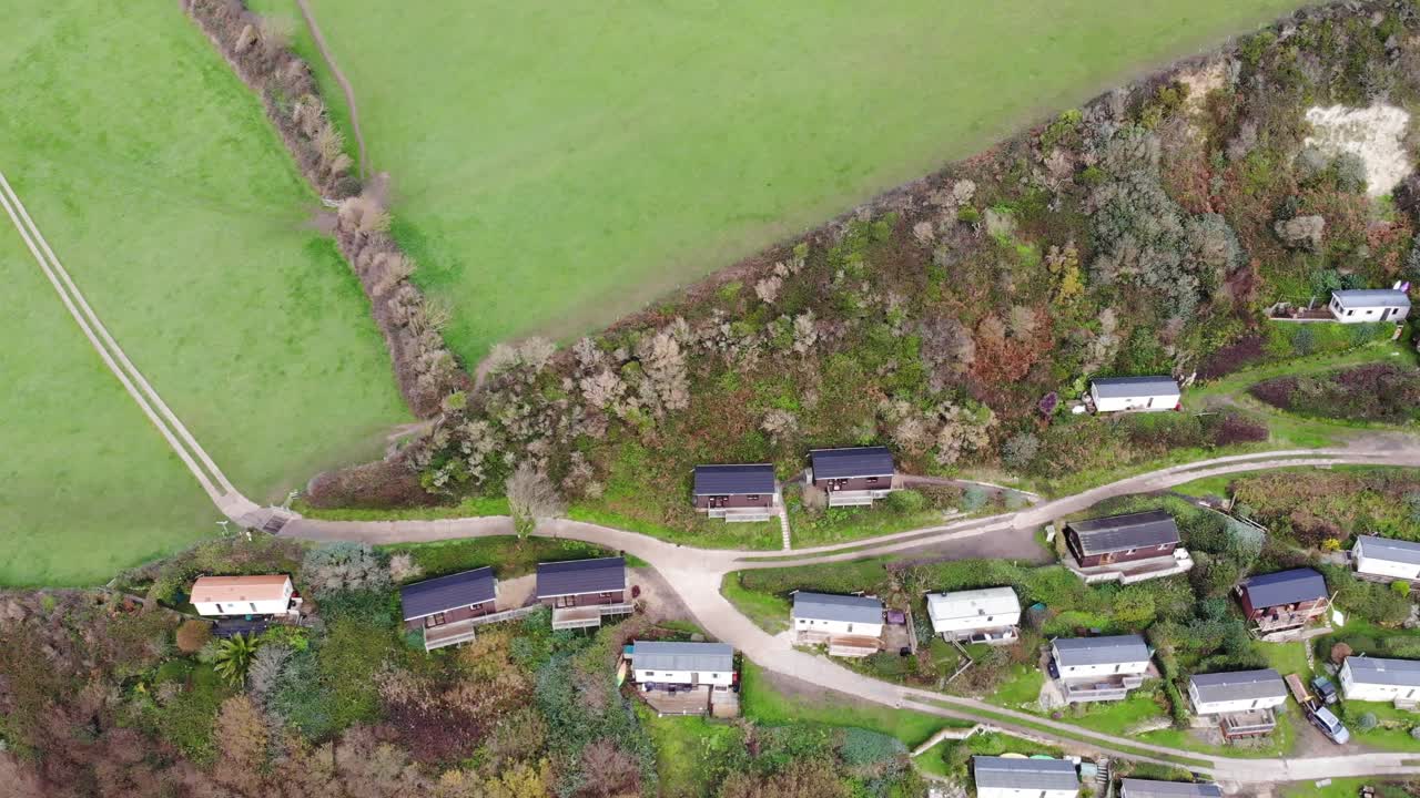 toma aérea suave de 4k que desciende lentamente hacia las casas y los campos ondulados de branscombe, devon, inglaterra
