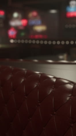 a close-up of a red leather booth in a dimly lit bar