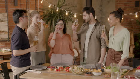 a multiethnic group of friends toasting with their glasses at a dinner party