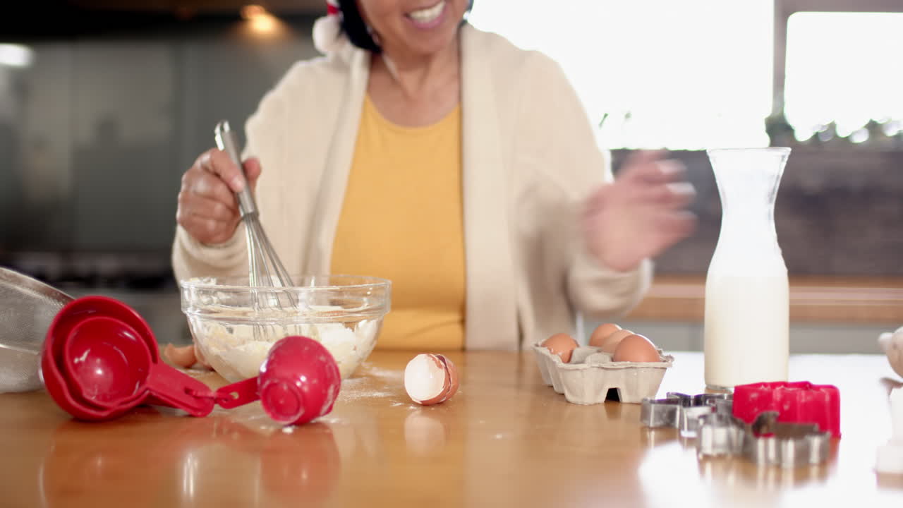 Smiling senior woman baking cookies at home, mixing ingredients in kitchen