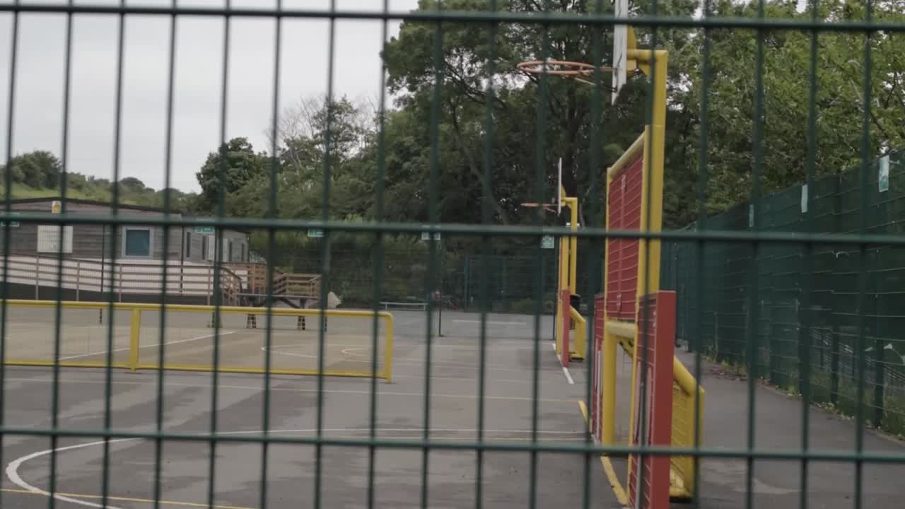 Panoramica a scorrimento di un parco giochi vuoto attraverso una recinzione