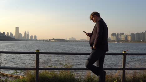 Man-in-sunglasses-watches-phone-on-the-beautifull-sunset-background