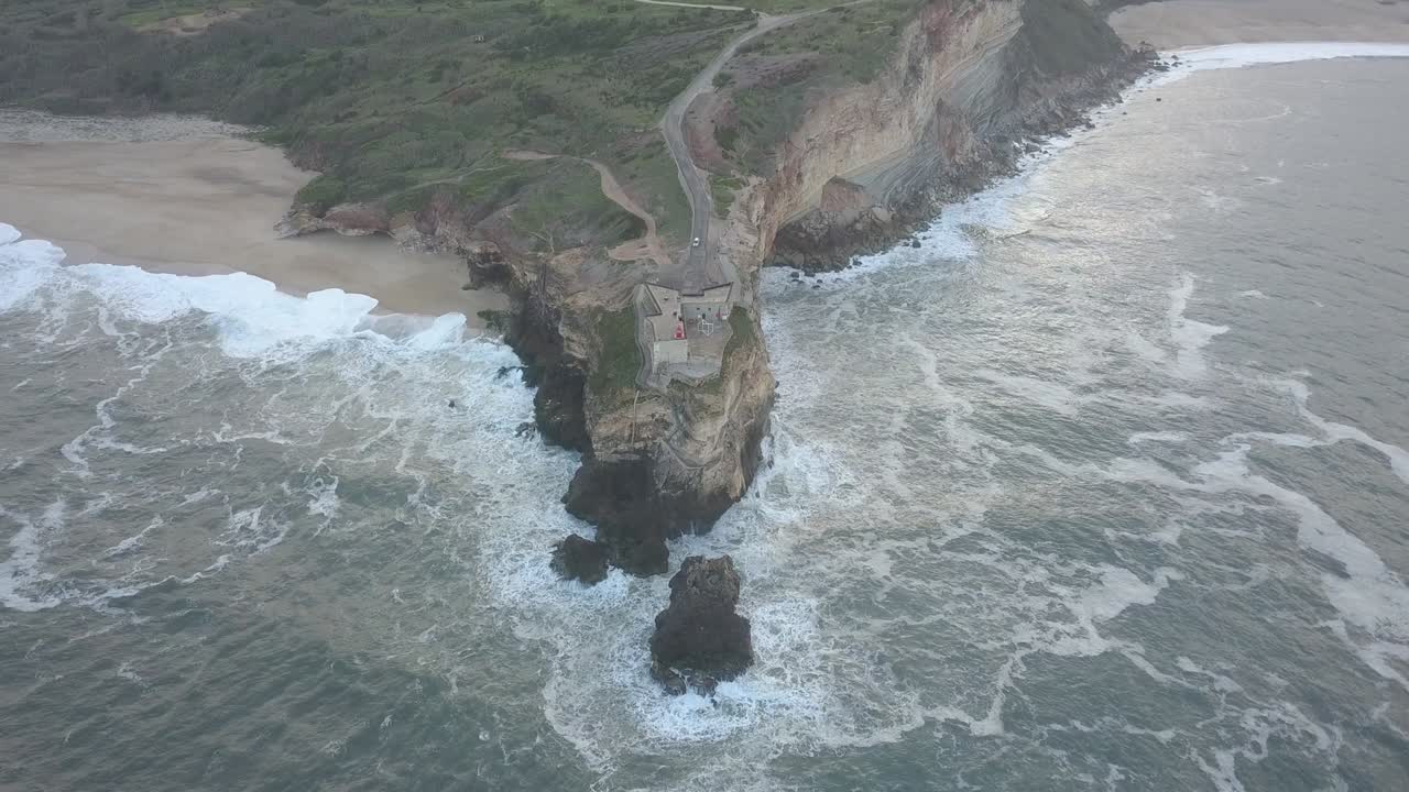 An iconic place on the Atlantic coast, the Mecca of big-wave surfing. View of Nazare's lighthouse in Zon North Canyon, place with the biggest waves in Europe, Nazare, Portugal