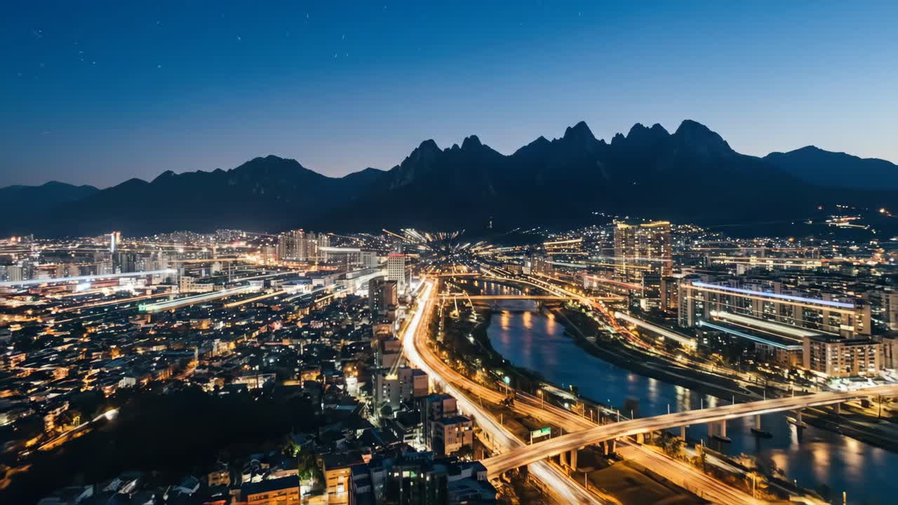 Time-lapse da Cidade à Noite com Rastros de Estrelas e Cenário de Montanha