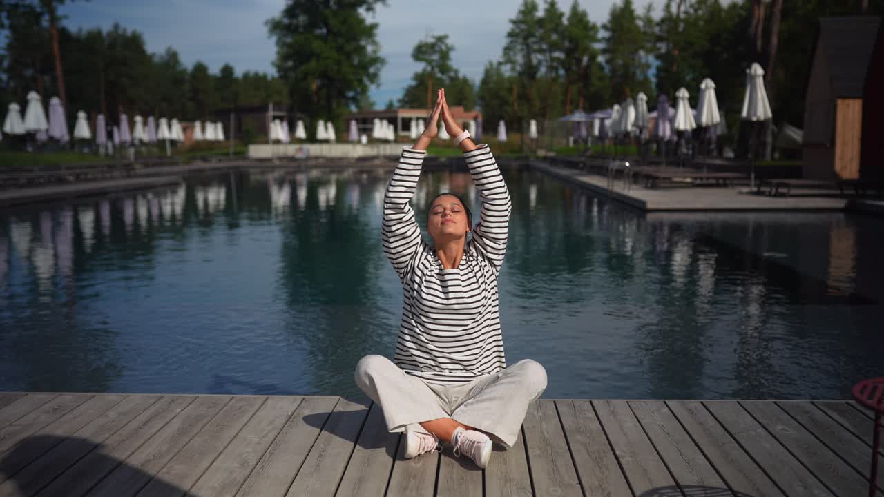 mujer meditando junto a una piscina