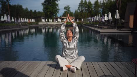 woman meditating by a pool